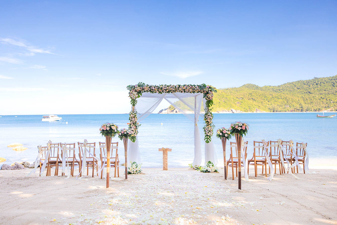 Heiraten auf Koh Phangan. Abbildung eines Hochzeitssetup am Strand. Blumendekoration und Stühlen